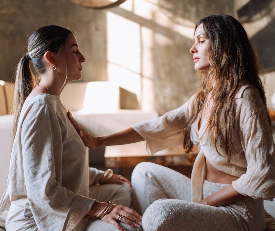 A facilitator resting a hand on a woman’s chest during a somatic session