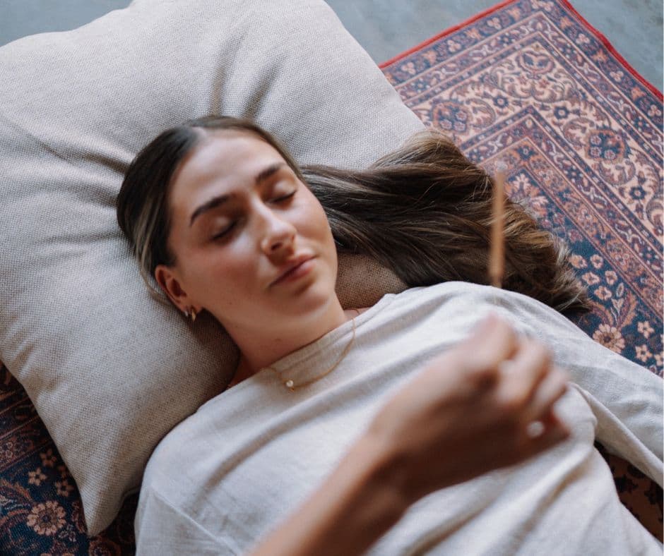 A woman resting on a cushion with her eyes closed during a guided meditation